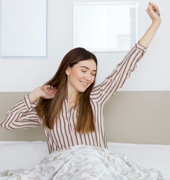 Woman waking refreshed and stretching in a bright bedroom
