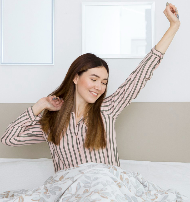 Woman waking refreshed and stretching in a bright bedroom